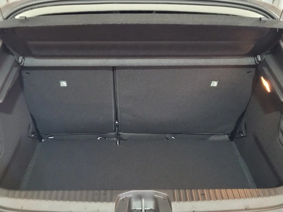 Coffre ouvert vu de l'arrière d'une Renault Clio gris foncé, montrant l'espace de chargement et la banquette arrière rabattable.