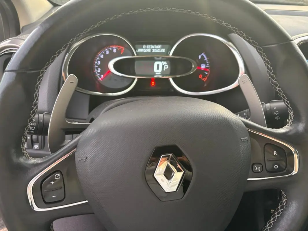 Vue rapprochée du volant cuir noir de la Renault Clio IV Estate avec commandes intégrées et tableau de bord digital.