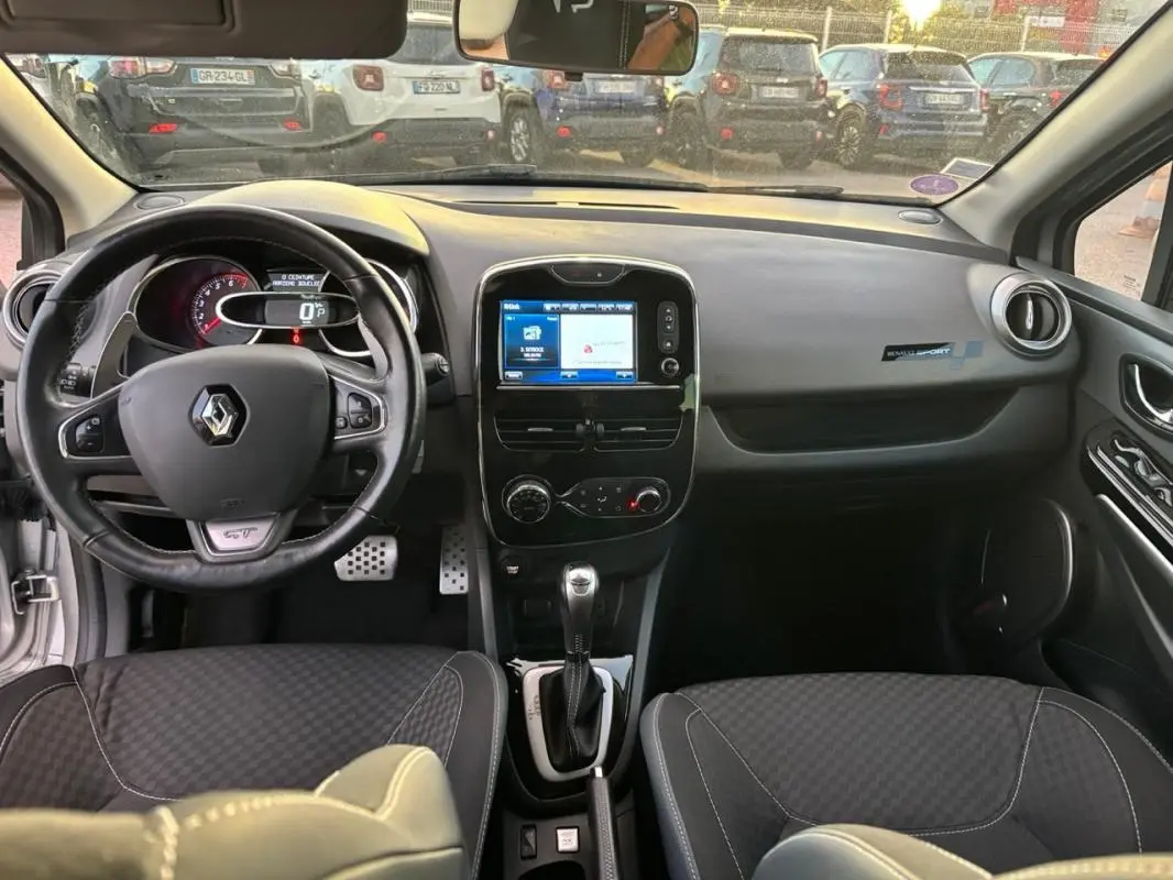 Vue intérieure avant de la Renault Clio IV Estate gris clair, volant cuir GT, écran tactile et levier de boîte automatique.