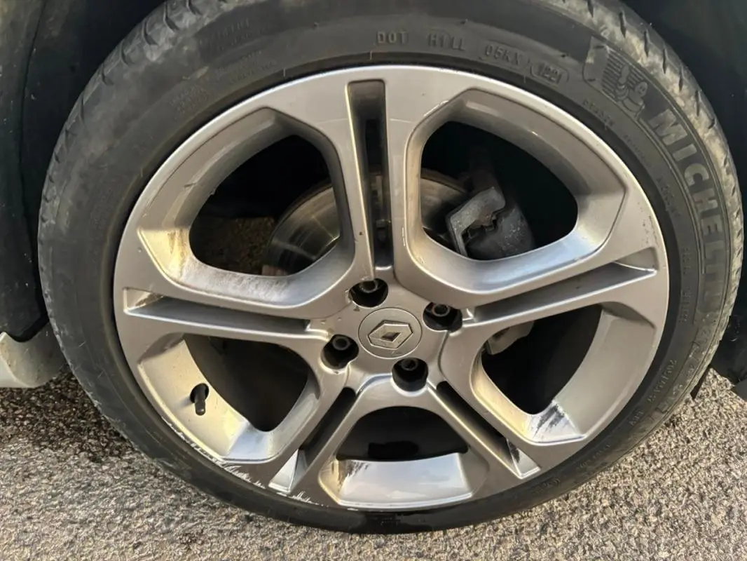 Gros plan sur la jante alliage 17 pouces gris clair d'une Renault Clio IV Estate TCe 120 GT EDC avec logo Renault central.