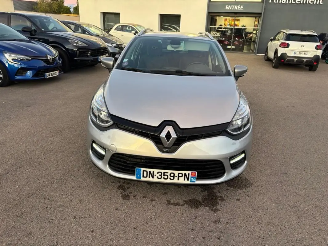 Vue avant d'une Renault Clio IV Estate gris clair avec calandre noire et feux diurnes LED allumés.