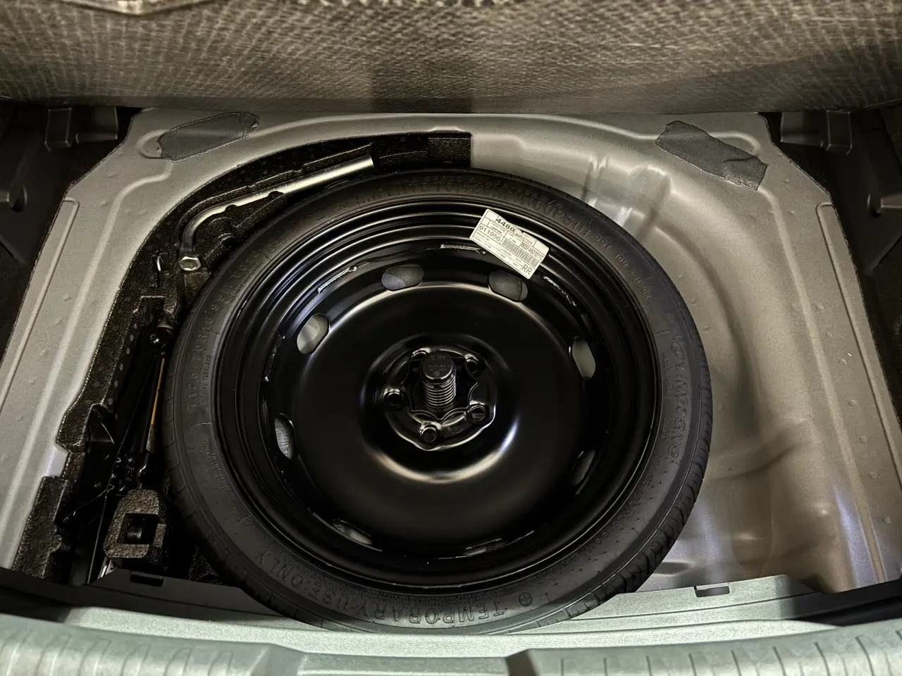 Vue plongeante sur la roue de secours noire dans le coffre d'une CUPRA Leon Gris Graphène 2026.