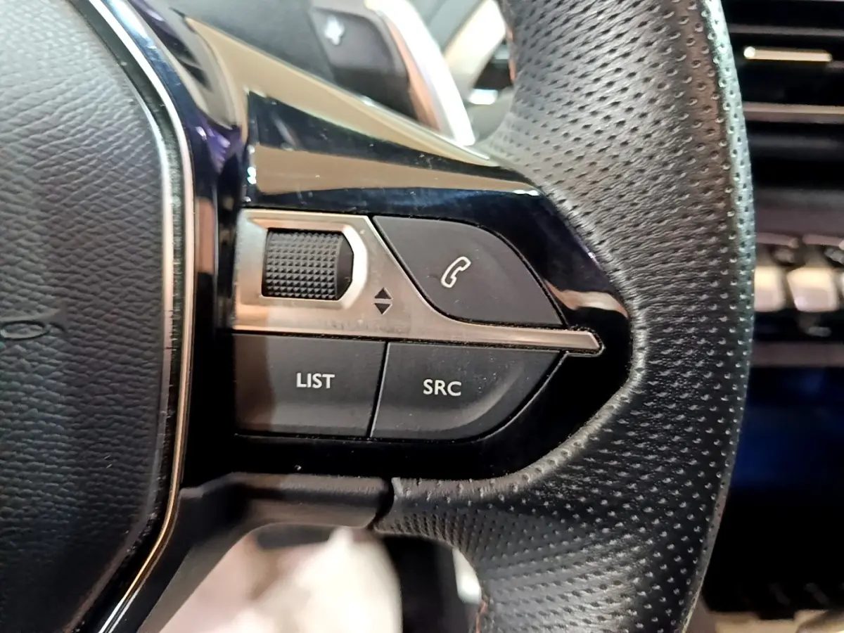 Gros plan sur les commandes gauche du volant cuir noir perforé du Peugeot 3008 GT Line gris foncé de 2020.
