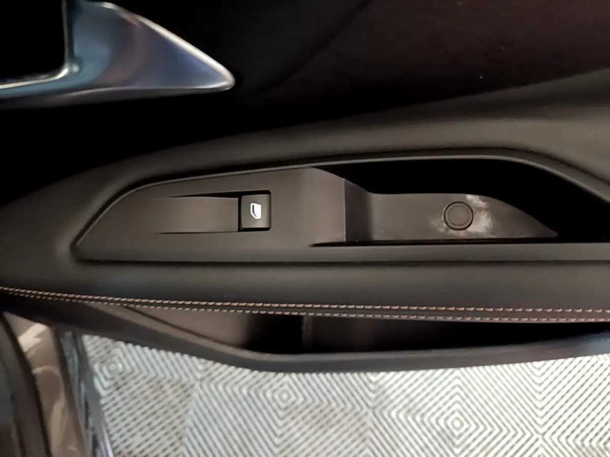 Gros plan sur la commande de lève-vitre côté conducteur du Peugeot 3008 gris foncé avec surpiqûres marron.
