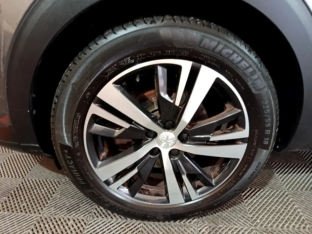 Gros plan sur la roue avant droite du Peugeot 3008 gris foncé, jante alliage bicolore et pneu Michelin.