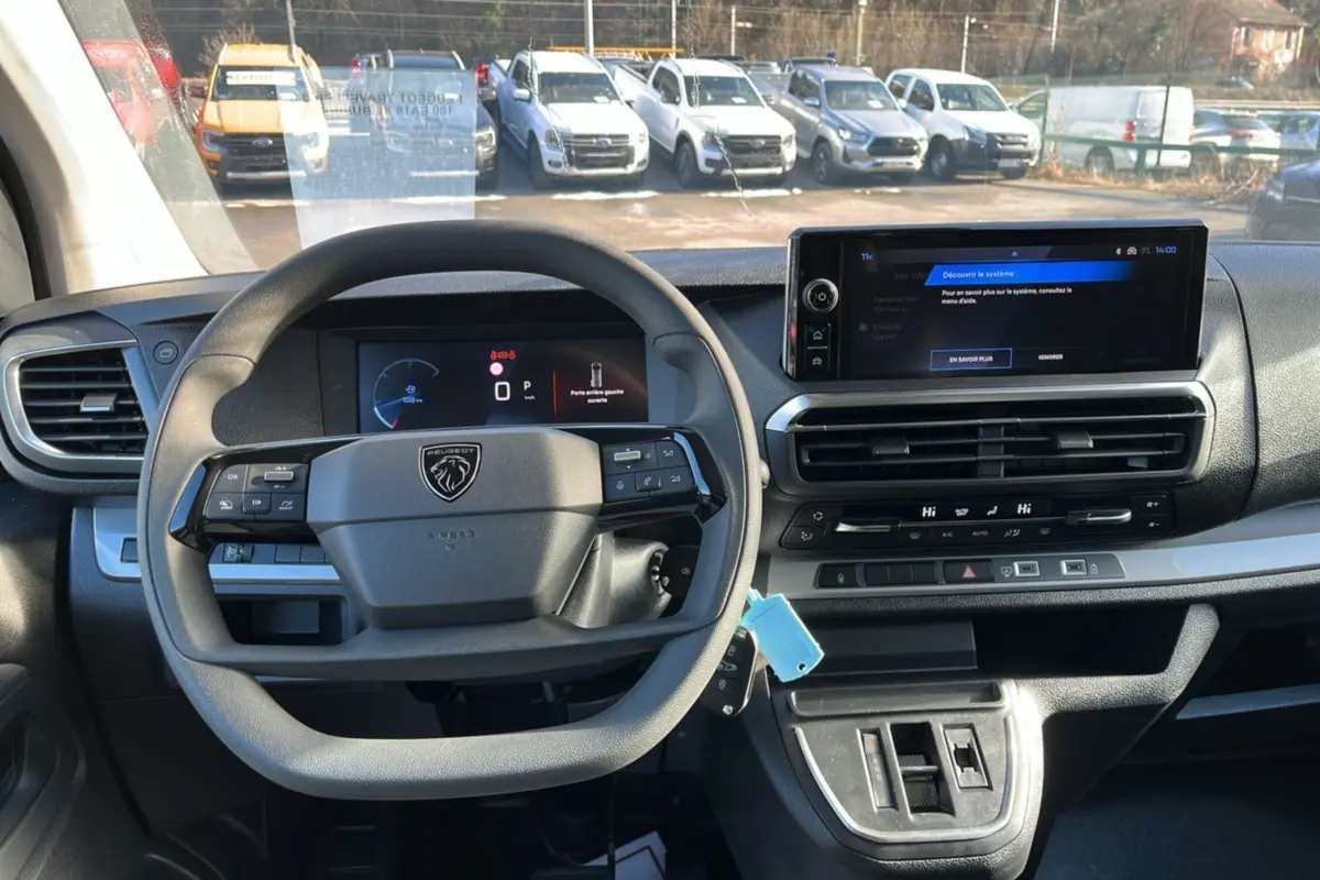Vue intérieure du poste de conduite du Peugeot Traveller gris titane, avec volant multifonctions et écran tactile central.