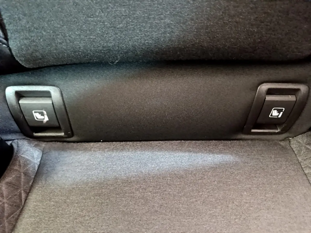 Détail des commandes de rabattement des sièges arrière sur la banquette tissu gris d’une Renault Clio Business Blue dCi 85 blanche.