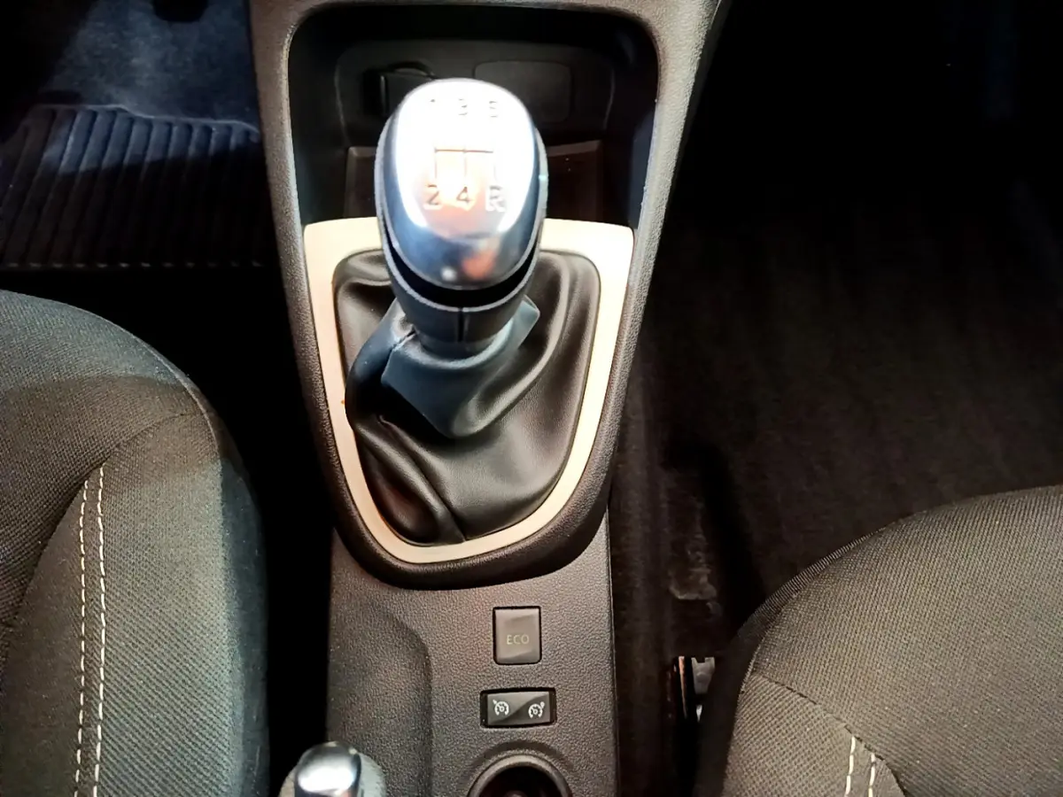 Le levier de vitesses manuel central de la Renault Captur Business gris foncé, entouré des sièges avant en tissu noir.