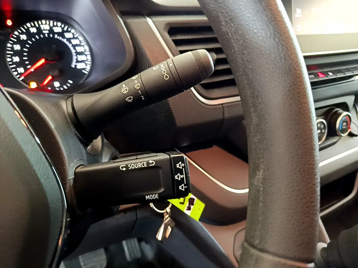 Gros plan sur le volant et les commandes multimédia du tableau de bord du Renault Trafic Fourgon blanc, version 2022.