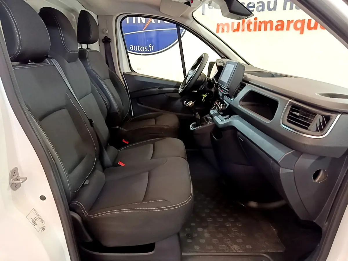 Vue intérieure côté conducteur du Renault Trafic Fourgon 2022 avec sièges noirs et tableau de bord moderne.
