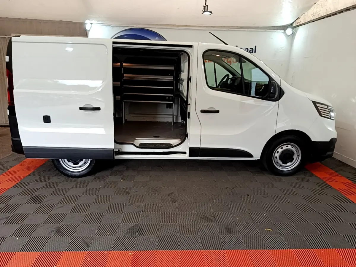 Renault Trafic Fourgon blanc vu de profil droit, porte latérale coulissante ouverte montrant l'intérieur utilitaire.