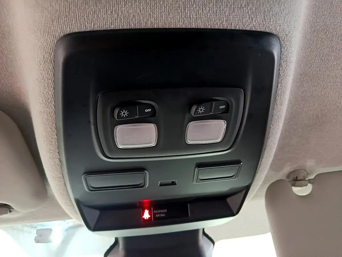 Vue en gros plan du plafonnier intérieur noir avec commandes d'éclairage et témoin airbag passager allumé du Renault Trafic blanc.