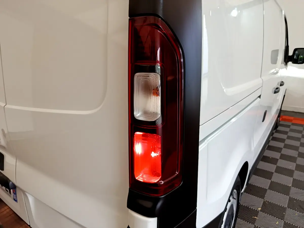 Feu arrière droit allumé sur un Renault Trafic Fourgon blanc vu de trois quarts arrière côté droit.