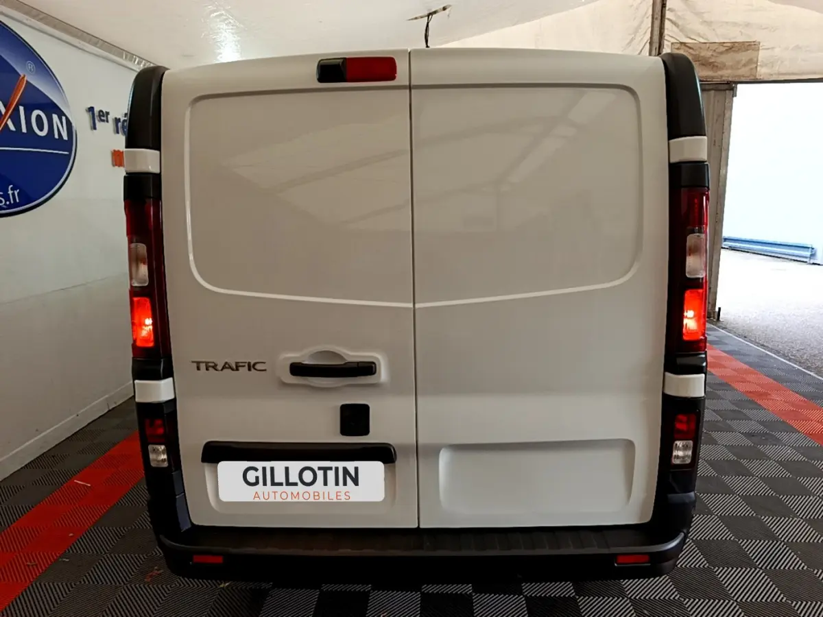 Vue arrière d'un utilitaire Renault Trafic Fourgon blanc avec feux arrière allumés et plaque GILLOTIN Automobiles.