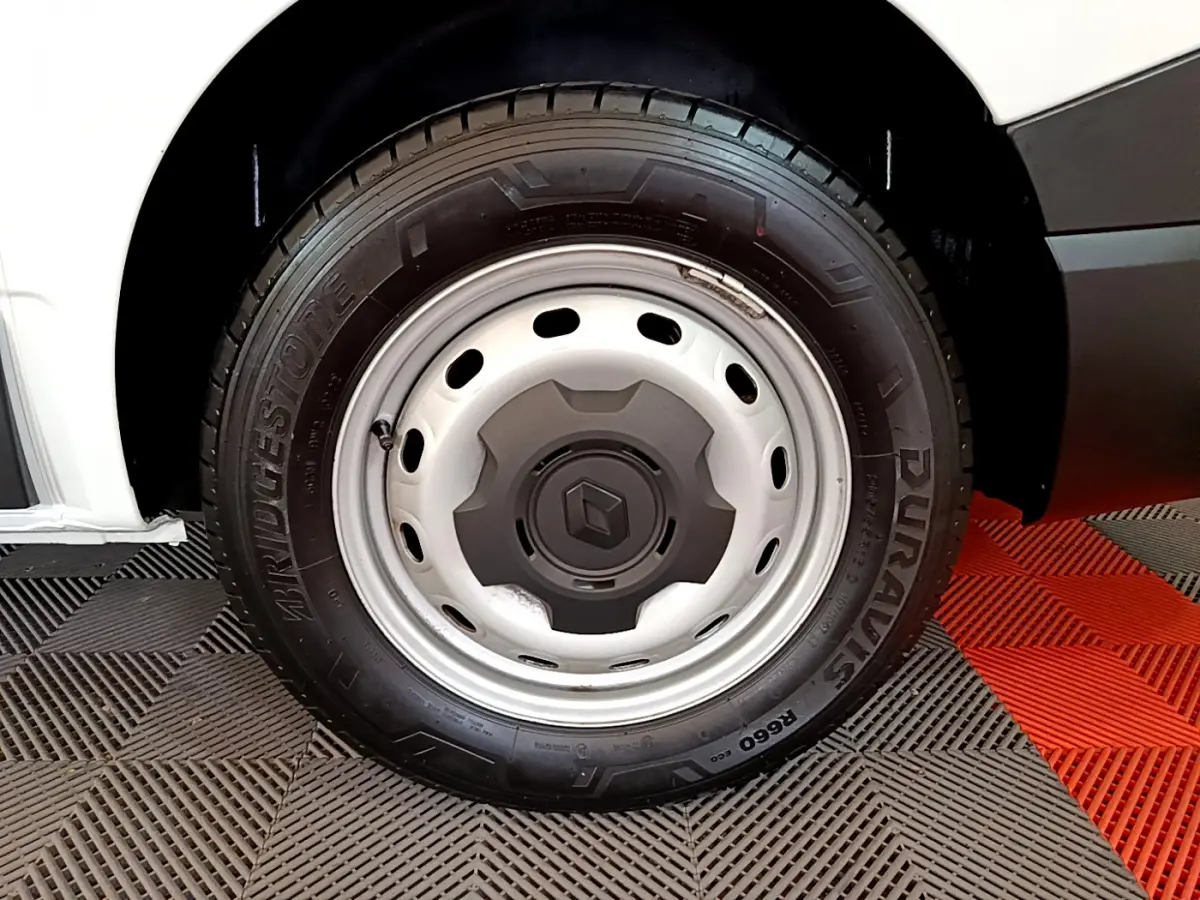 Gros plan sur la roue avant gauche du Renault Trafic Fourgon blanc, jante acier avec logo Renault central.