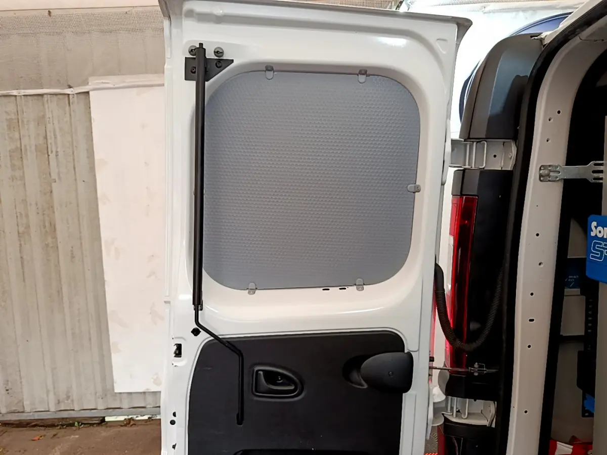 Vue rapprochée de la porte arrière gauche ouverte du Renault Trafic Fourgon blanc, montrant la cloison pleine intérieure.
