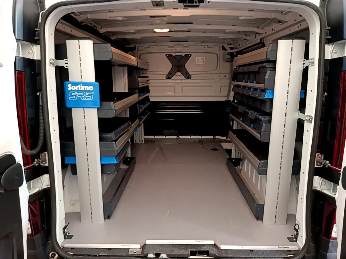 Vue arrière intérieure du fourgon blanc Renault Trafic FG CF L1H1 2022 avec étagères de rangement Sortimo SR5.