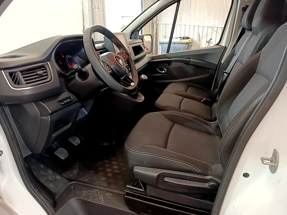 Intérieur du Renault Trafic Fourgon blanc 2022, vue côté conducteur montrant le tableau de bord et les sièges noirs.
