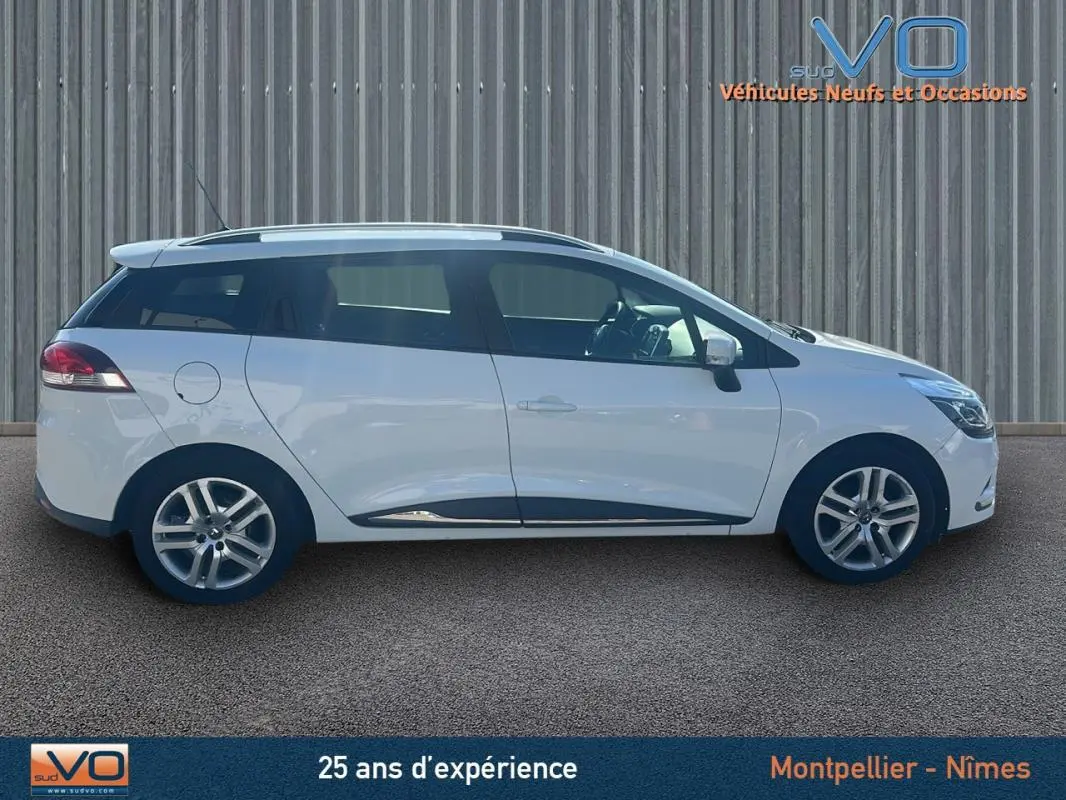 Profil latéral droit d'une Renault Clio IV Estate Business blanche avec vitres surteintées et jantes alliage visibles.