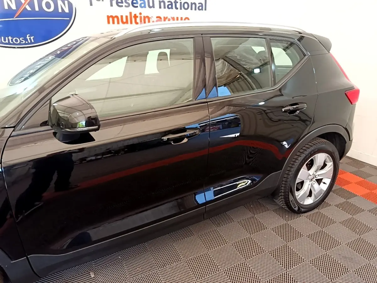 Vue latérale droite du Volvo XC40 noir 2020 avec jantes alliage et rétroviseurs électriques dans un showroom.