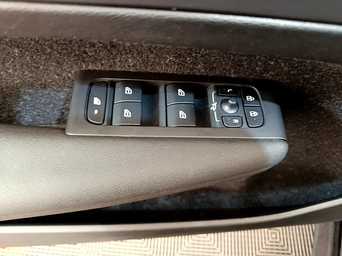 Gros plan sur les commandes de lève-vitres et rétroviseurs sur la porte intérieure côté conducteur d’un Volvo XC40 noir.
