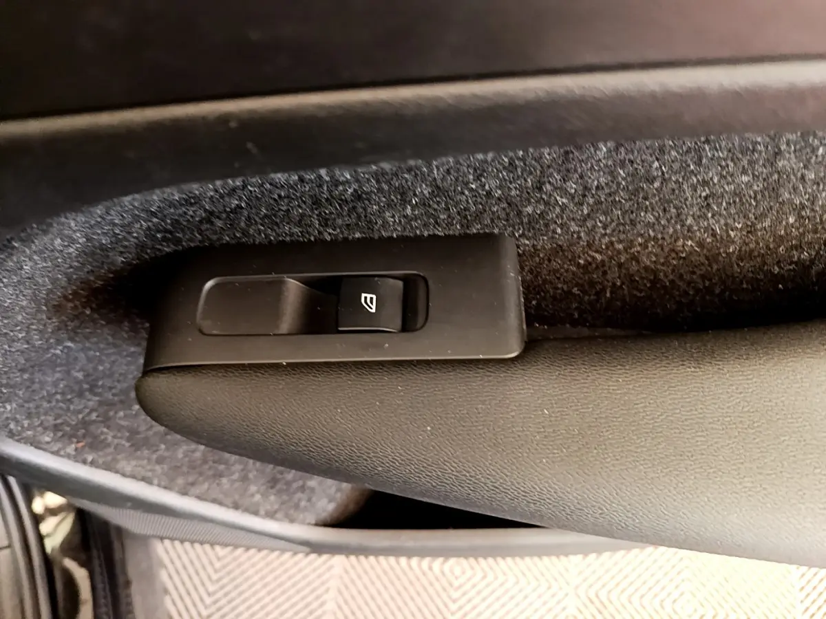 Gros plan sur le bouton de commande de la vitre électrique côté porte intérieure d’un Volvo XC40 noir.