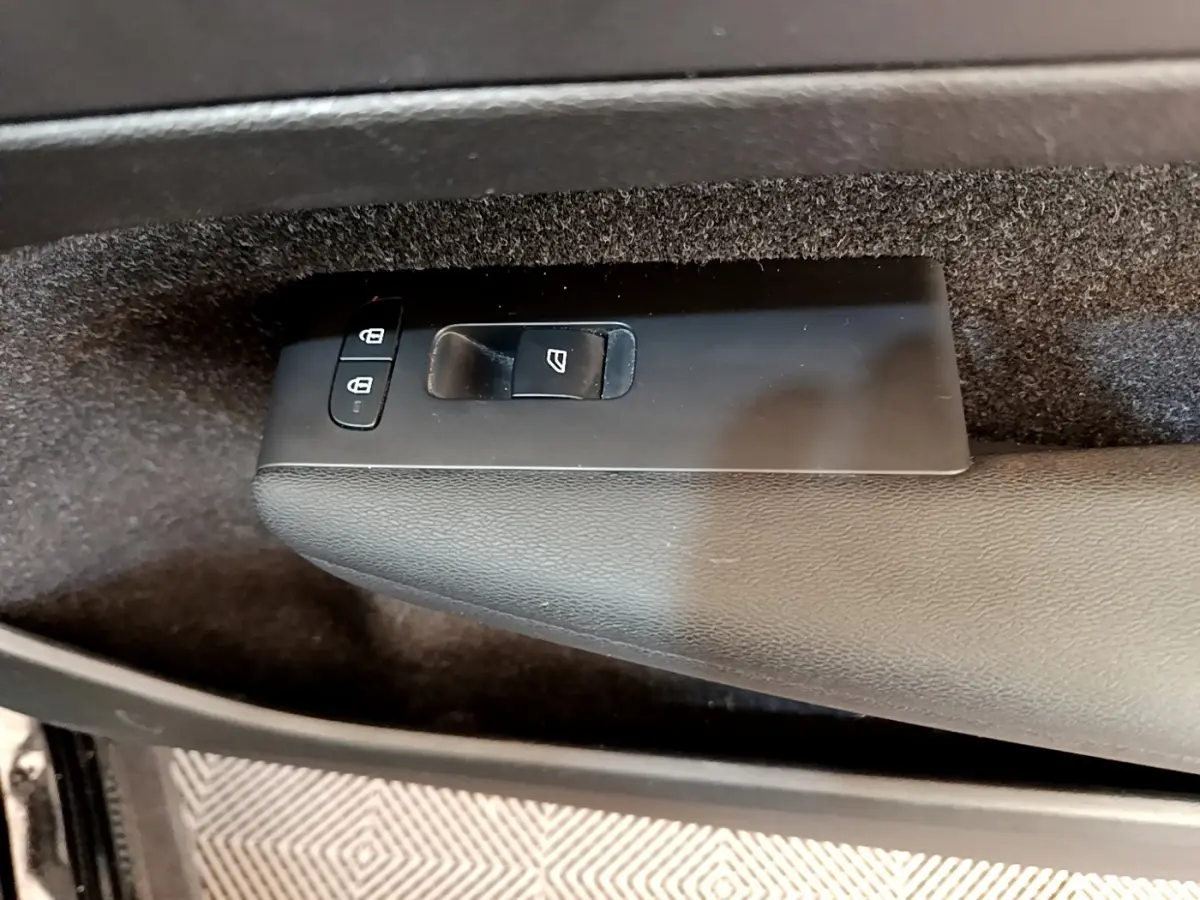 Gros plan sur les commandes de lève-vitre et verrouillage sur la porte intérieure côté conducteur d’un Volvo XC40 noir.