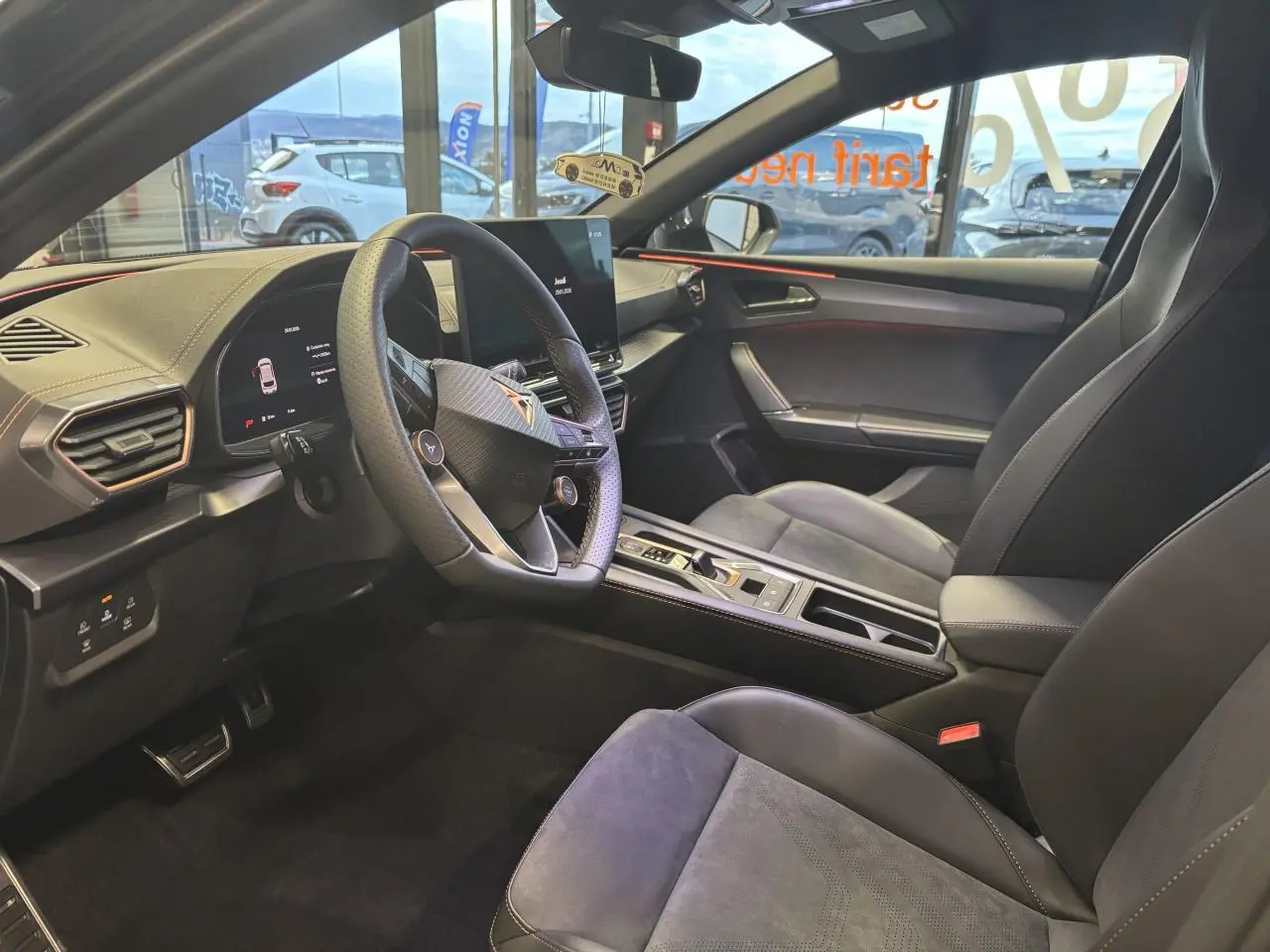 Intérieur avant droit de la CUPRA Leon gris Magnetic, sièges baquets suédine noire avec surpiqûres cuivrées et volant cuir.