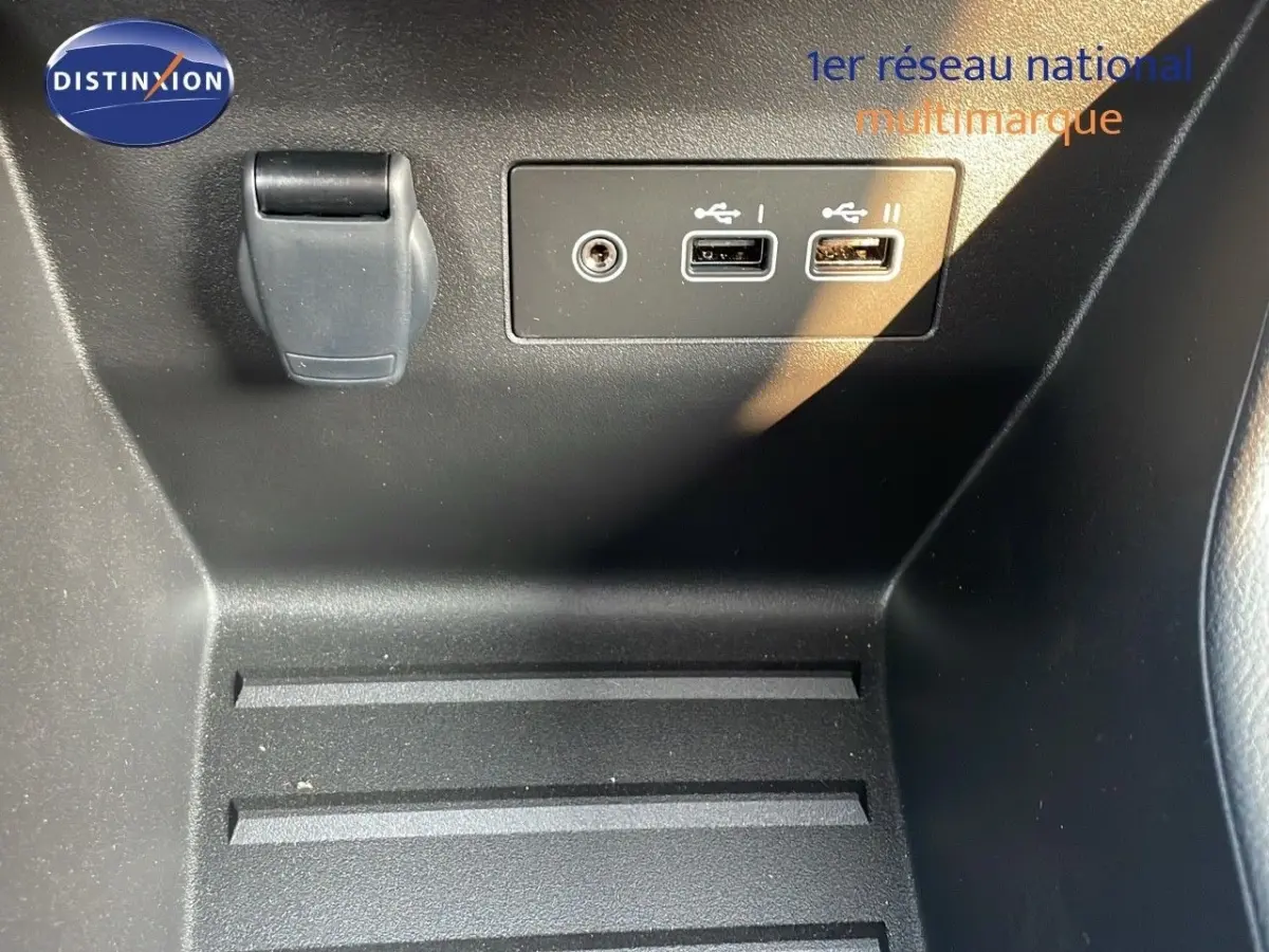 Gros plan sur la console centrale noire de la Renault Clio Evolution Blue dCi 100 avec ports USB et prise auxiliaire.