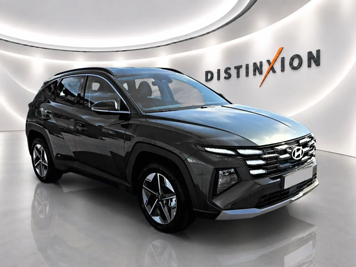 Vue 3/4 avant d'un Hyundai Tucson vert foncé avec jantes alliage et calandre distinctive dans un showroom lumineux.
