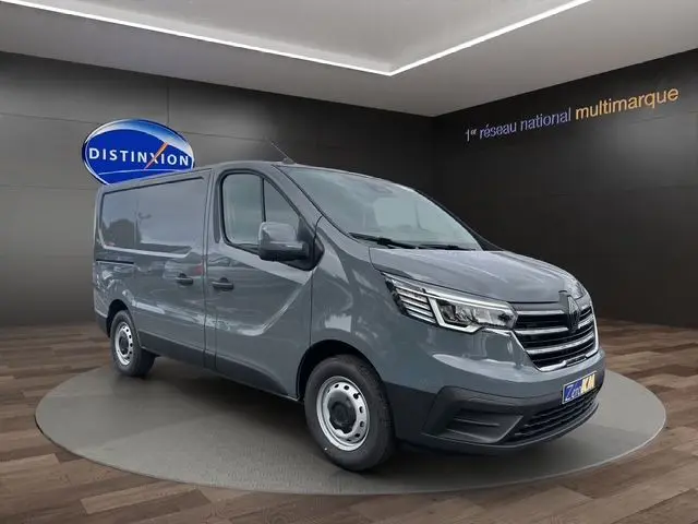 Renault Trafic Fourgon L1H1 gris urbain, vue 3/4 avant droit, avec jantes acier et calandre noire distinctive.