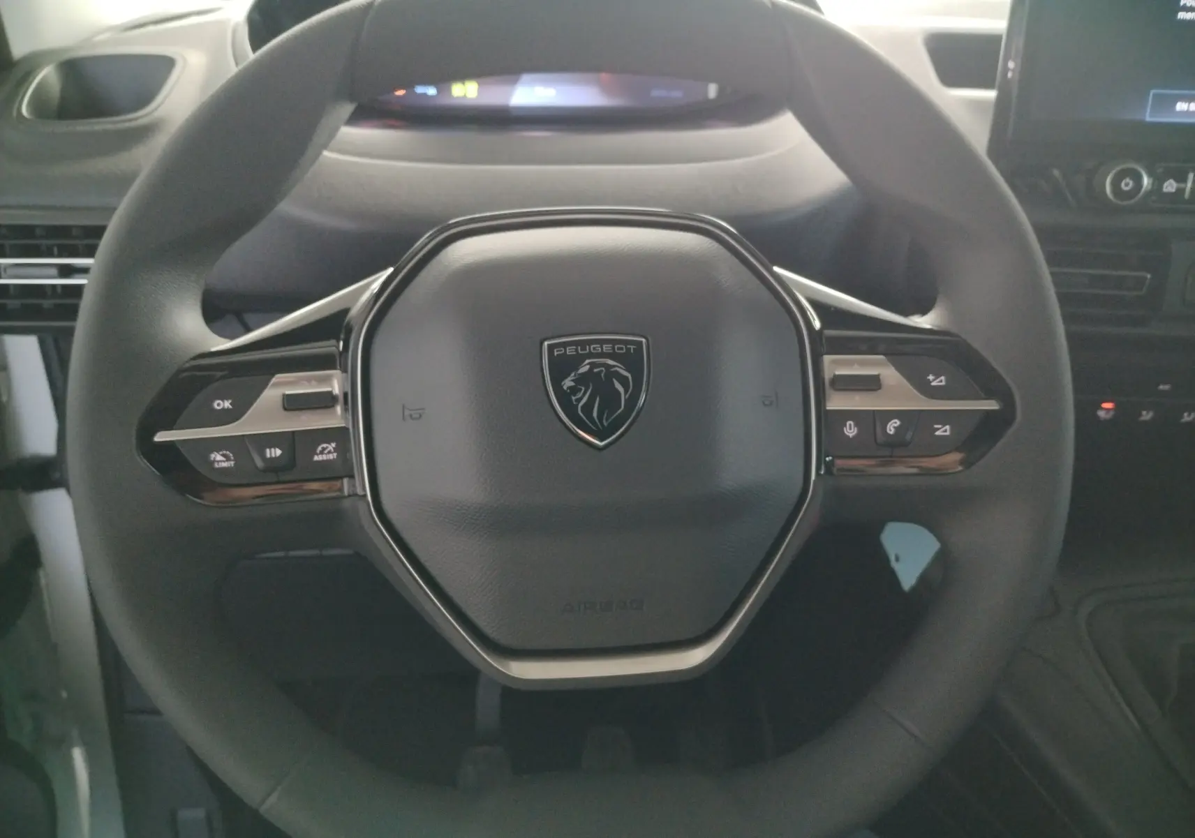 Vue rapprochée du volant multifonction noir du Peugeot Partner FGN 2025 avec commandes intégrées et logo central.