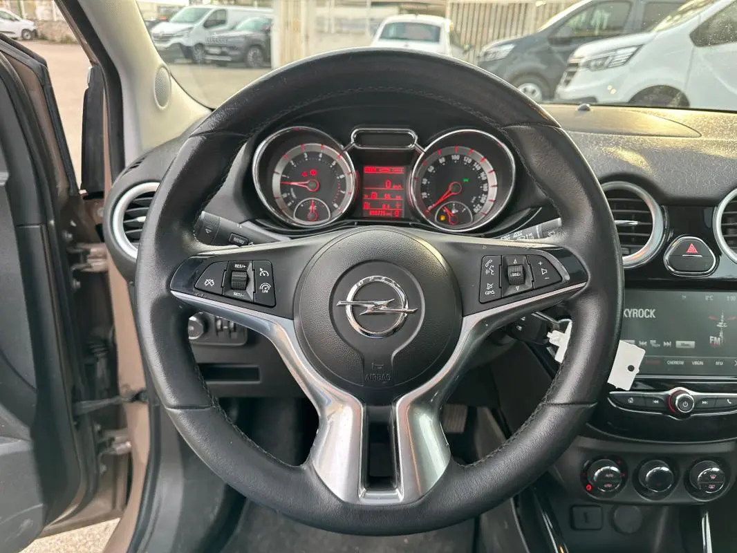 Vue intérieure centrée sur le volant cuir multifonctions d'une Opel Adam marron avec tableau de bord et écran tactile.