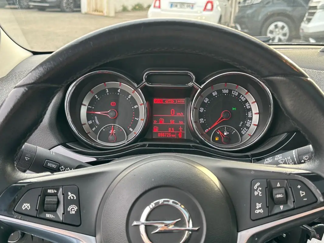 Vue rapprochée du tableau de bord et volant cuir noir d'une Opel Adam 2016 avec commandes multifonctions visibles.