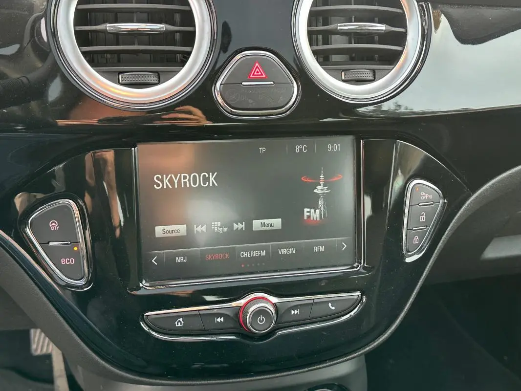 Vue rapprochée de la console centrale noire brillante de l'Opel Adam avec écran tactile affichant la radio Skyrock.