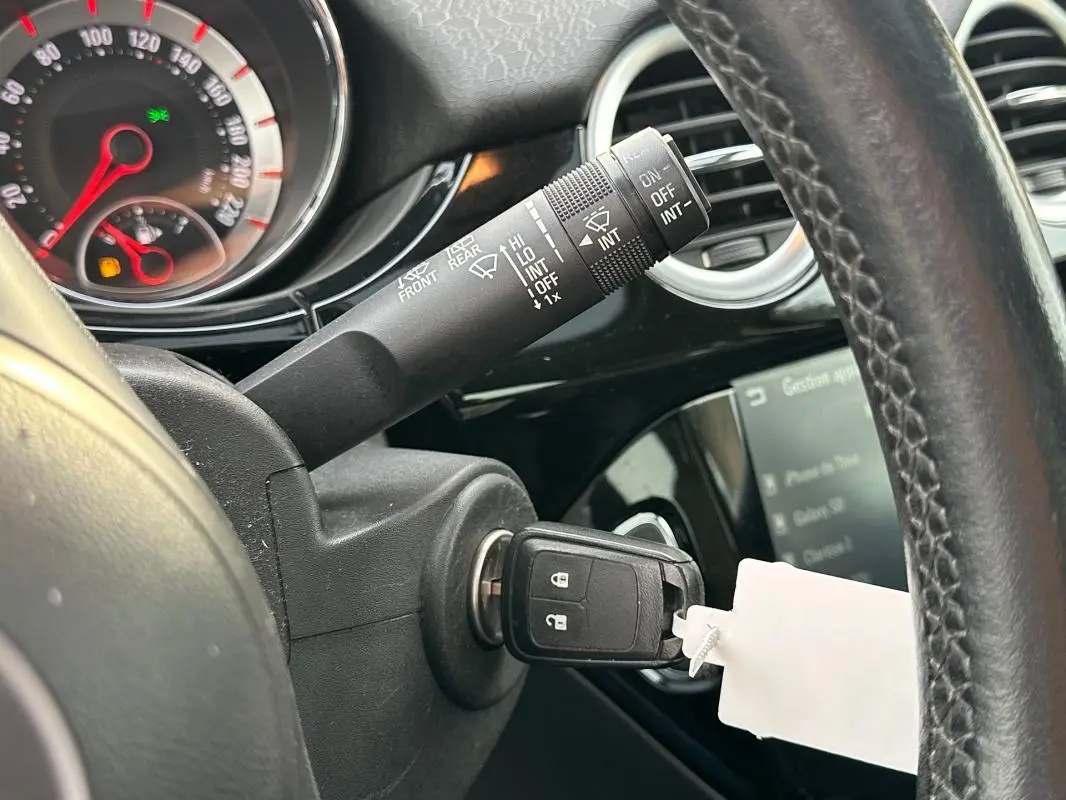 Gros plan sur le volant cuir et le contacteur avec clé insérée dans l'Opel Adam 2016, intérieur noir brillant.