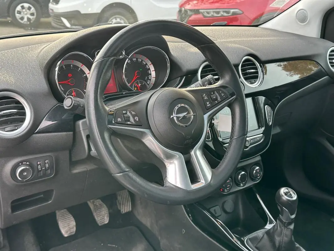Vue intérieure du tableau de bord de l'Opel Adam 2016, volant cuir multifonctions et levier de vitesse manuelle visibles.