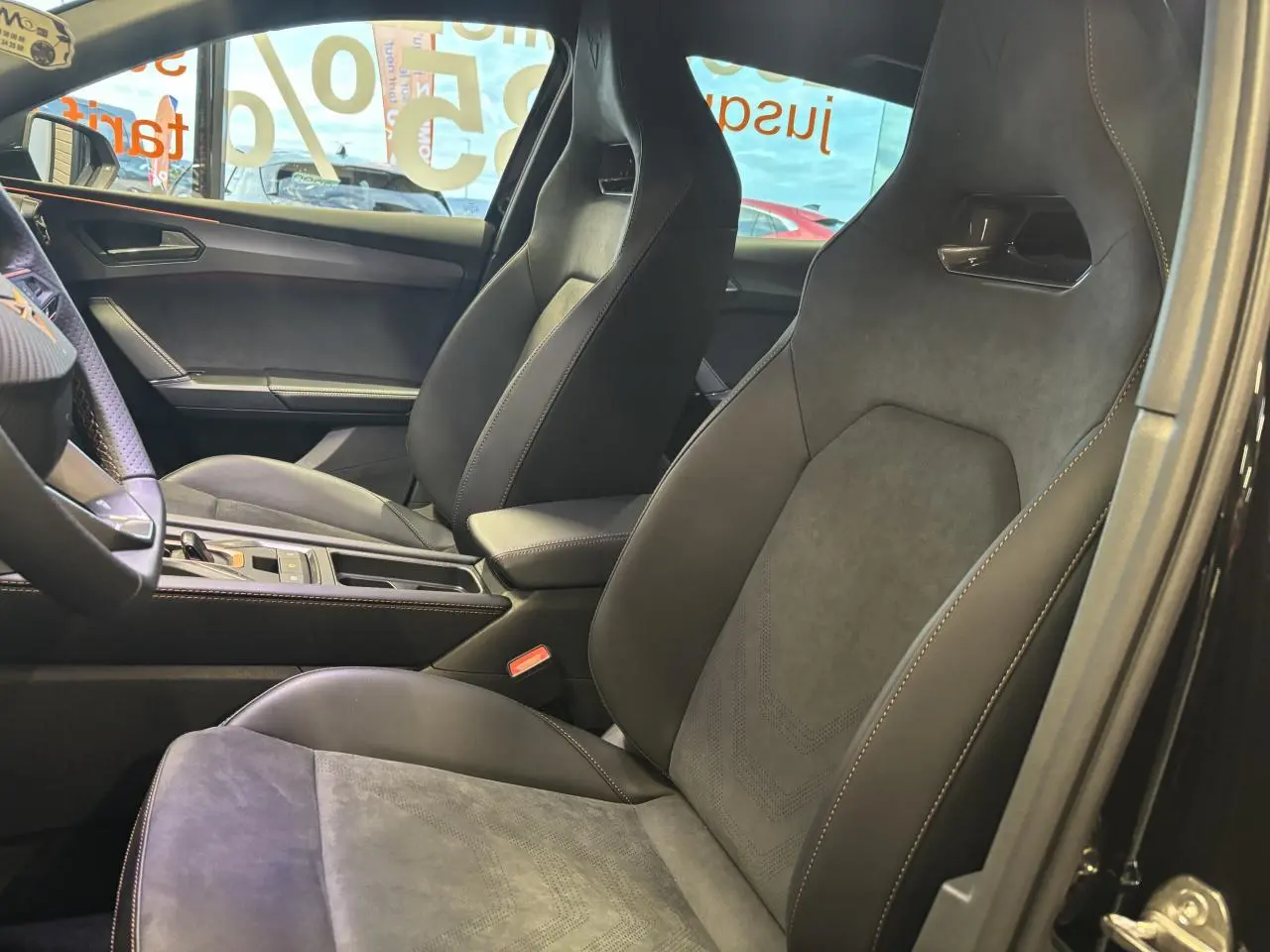 Vue intérieure côté droit des sièges baquets suédine noir et cuir du CUPRA Leon 2026 avec surpiqûres cuivrées et console centrale.