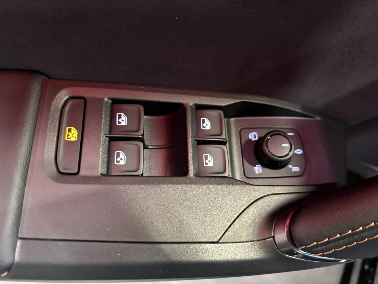 Gros plan sur les commandes de lève-vitres et rétroviseurs côté conducteur d'une CUPRA Leon noir midnight.