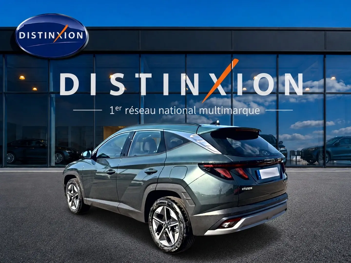 Vue 3/4 arrière droite d'un Hyundai Tucson vert métallisé stationné devant une vitrine Distinxion.