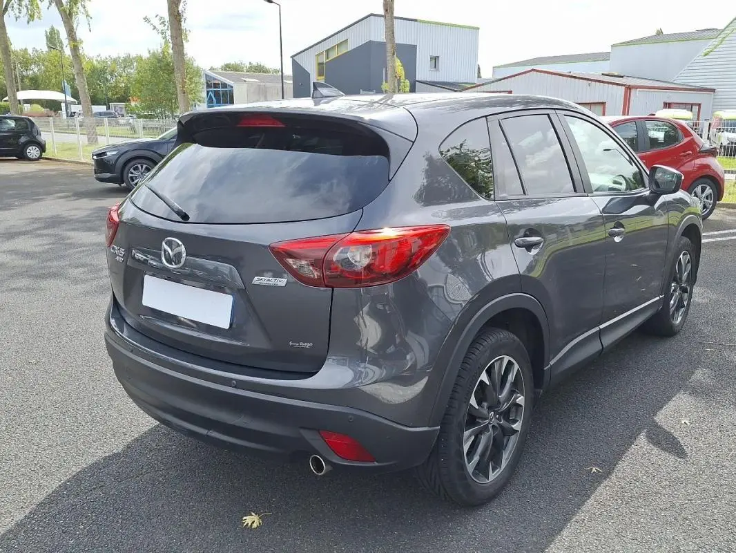 Vue 3/4 arrière droite d'un Mazda CX-5 gris métallisé avec jantes alliage et vitres surteintées.