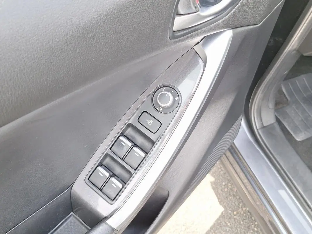 Gros plan sur la porte avant gauche gris clair du Mazda CX-5 avec commandes électriques des vitres et rétroviseurs.