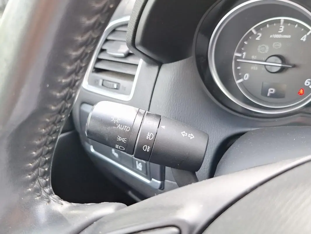 Gros plan sur la manette des feux et clignotants à gauche du volant en cuir du Mazda CX-5 gris 2015.