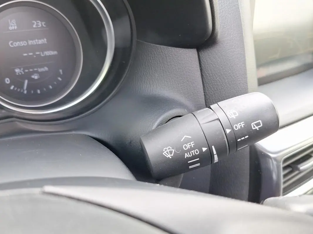 Gros plan sur la commande d'essuie-glace à droite du volant du Mazda CX-5 gris, tableau de bord en arrière-plan.