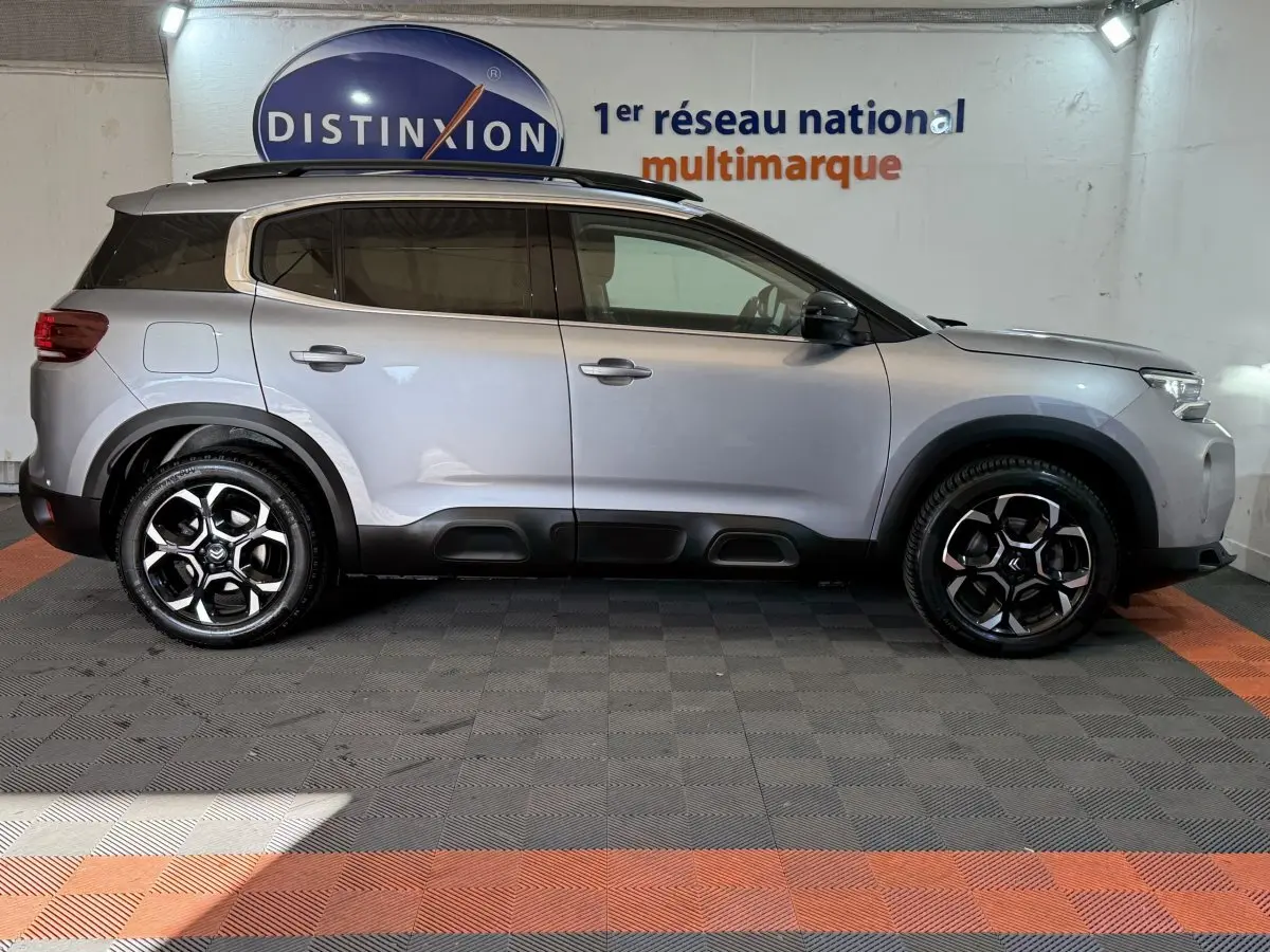 Vue de profil côté droit d'un Citroën C5 Aircross gris clair avec jantes noires et protections noires basses.