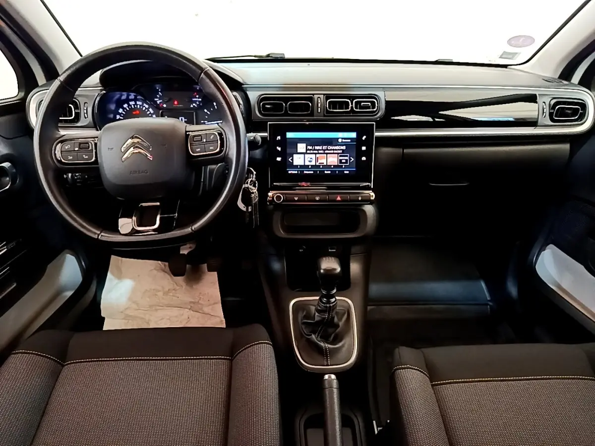 Vue intérieure avant du tableau de bord et volant cuir noir d'une Citroën C3 blanche avec écran tactile central.