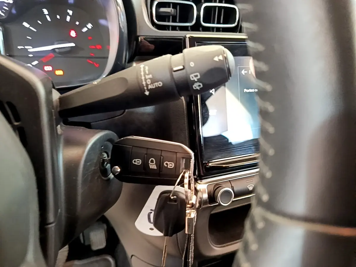 Gros plan intérieur sur le volant et la clé insérée du Citroën C3 blanc, avec tableau de bord et écran tactile visibles.