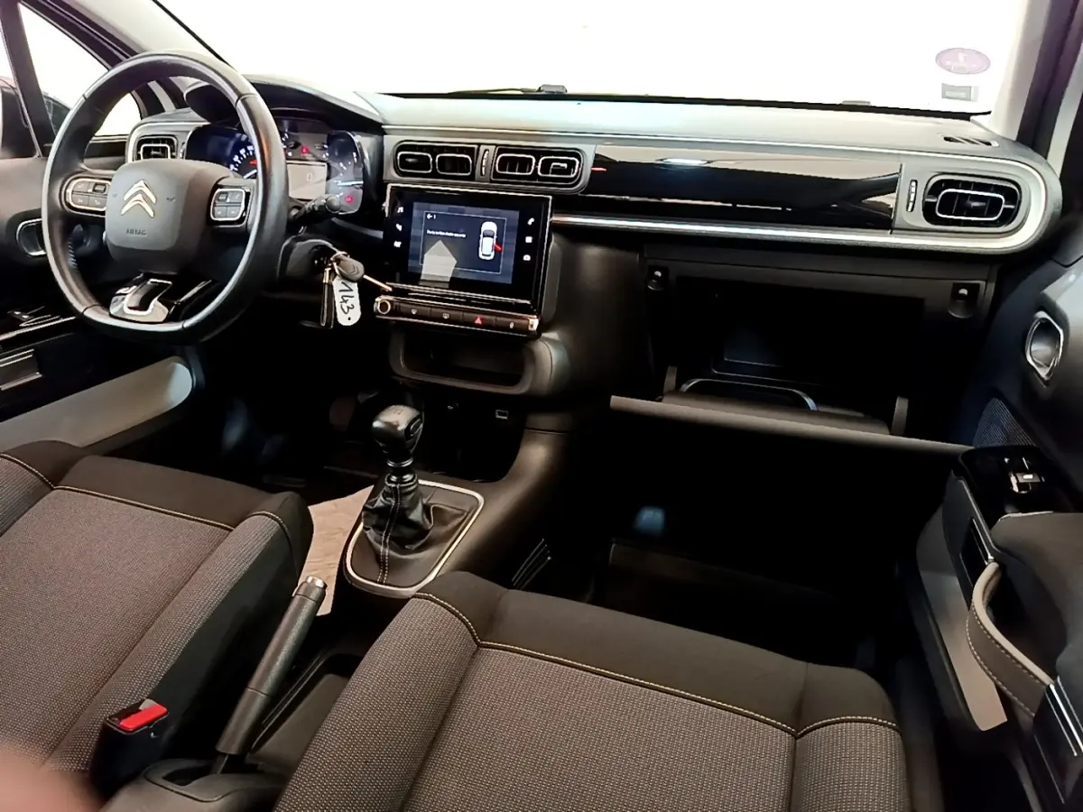 Vue intérieure avant de la Citroën C3 blanche 2021, tableau de bord noir avec écran tactile et volant cuir multifonctions.