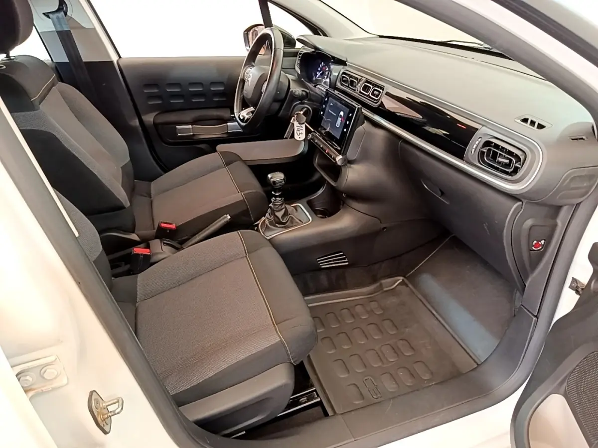 Intérieur côté conducteur de la Citroën C3 blanche, vue 3/4 avant, avec tableau de bord noir et écran tactile central.