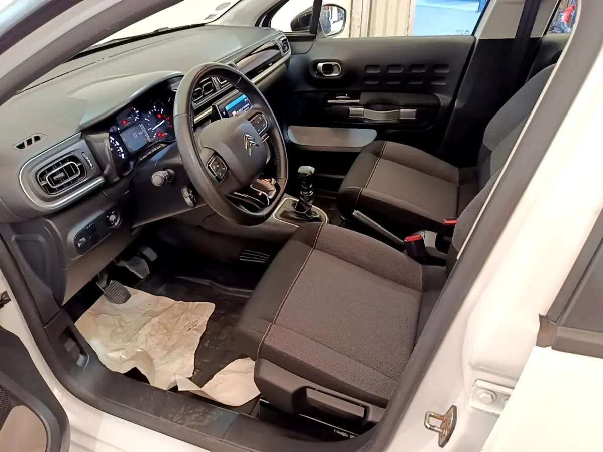 Intérieur de la Citroën C3 blanche, vue côté conducteur, avec tableau de bord noir et volant cuir multifonctions.
